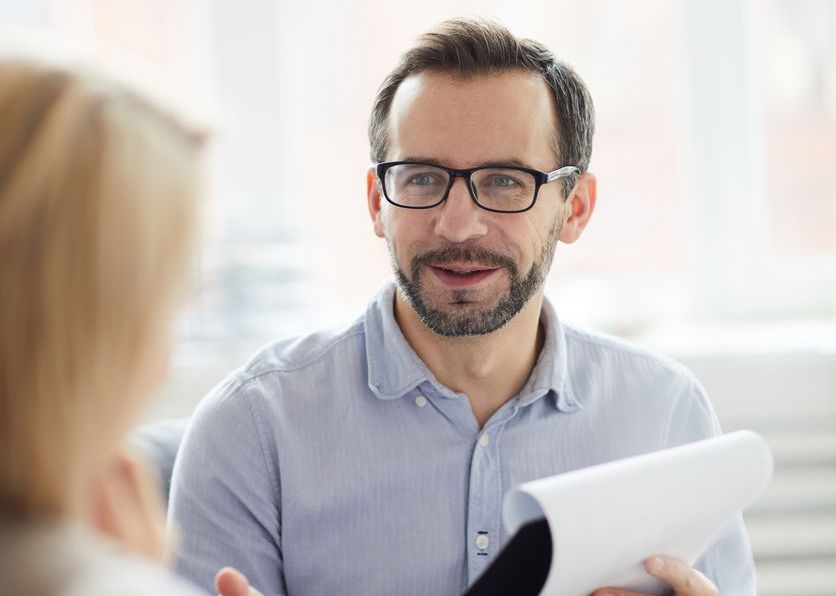 Confident counselor with document giving advice to his patient while discussing ways of solving her problem